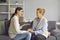 Happy daughter and understanding supportive senior mother sitting on sofa and talking