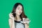 Happy delicious young Asian girl eating chocolate cake over green isolated background