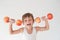 Happy delightful active strong small laughing kid in tank top lifting dumbbells made from apple fruits easy during workout