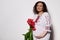 Happy delightful pregnant woman holding a bouquet of tulips, caressing her belly, smiling at camera on white background