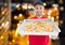 Happy deliveryman showing the pizza in the city at night. Lights