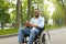 Happy disabled black man in wheelchair using smartphone, checking messages online at park