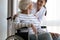 Happy disabled older woman sitting in wheelchair, talking with caregiver