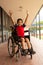 Happy disabled schoolboy with arms up looking at camera in corridor