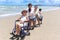 Happy disabled senior elderly woman in wheelchair spending time together with family on holiday beach. Asian grandma, daughter,