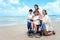 Happy disabled senior elderly woman in wheelchair spending time together with her family on tropical beach. Asian grandma,