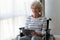 Happy disabled senior woman sit on wheelchair using digital tablet