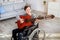 Happy disabled teenager in wheelchair playing acoustic guitar, composing songs at home, above view