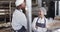 Happy diverse bakers in bakery kitchen with arms crossed talking in slow motion