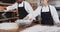 Happy diverse bakers working in bakery kitchen, pouring flour on counter in slow motion