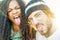 Happy diverse culture friends making funny faces in phone camera - Multi ethnic couple taking selfie outdoor with back light -