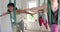 Happy diverse fitness teenage girls exercising in aerial yoga class in big white room, slow motion