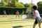 Happy diverse group of friends playing tennis at tennis court