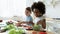 Happy diverse little girls sisters preparing food in kitchen together