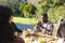 Happy diverse male and female friends eating thanksgiving celebration meal in sunny garden