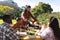 Happy diverse male and female friends serving thanksgiving celebration meal in sunny garden