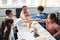 Happy diverse schoolchildren putting hands together at classroom