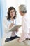 Happy Doctor With Clipboard Looking At Patient