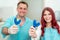 Happy doctor dentist with his patient show the result of impressions of her teeth on a spoon with silicone material