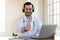 Happy doctor in wireless earphones recommending contact to medical hotline