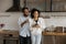 Happy dreamy African American couple drinking hot beverages in kitchen