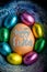 Happy Easter 2017 lettering on egg lined with small chocolate eggs wrapped in colorful foil. Vertical image.