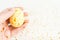 Happy Easter background. Closeup handpainted white egg with gold design in female hand with gold stars on white