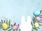Happy Easter border with bunny paper template, colored eggs, palm leaves on blue background