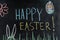Happy Easter on chalk board, egg and spring flower, grass and easter bunny ears