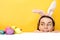 Happy easter! Charming cheerful happy woman begin to hunt for Easter eggs, wears fluffy ears, poses over yellow background