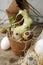 Happy Easter concept - Easter eggs and bunny rabbit in flower craft potty and fresh greenery branches on dark rustic wooden