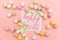 Happy Easter concept. Inscription HAPPY EASTER letters candy chocolate eggs and jellybean sweets isolated on trendy pastel pink