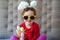 Happy Easter. cute beautiful girl with curly hair, sunglasses and bunny ears sitting on the sofa with colorful easter eggs.