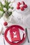 Happy easter. Decor and table setting of the Easter table is a vase with white tulips and dishes of red and white color. Easter