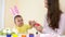 Happy Easter family mother and baby painting eggs at home seasonal traditions with bunny ears