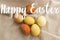 Happy Easter greeting card. Happy Easter text sign handwritten on  modern brown and yellow easter eggs flat lay on rustic linen