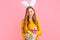 Happy Easter. happy young woman wears rabbit ears on Easter day and holds a basket of Easter eggs, on an isolated pink background
