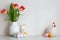Happy Easter home decor. Table with vase of tulips, colorful Easter eggs, decorative bunny and chicken