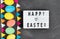 Happy easter lettering on white board with colorful painted eggs and felt garland on chalk board