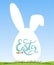 Happy easter lettering on white silhouette of easter egg and bunny ears. White egg on spring natural background with meadows and