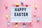 Happy Easter text on lightbox on pink pastel paper background with yellow, pink, blue eggs and bunnies. Bright template for Easter