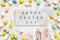 Happy Easter written on backdrop,  decorative Easter eggs and Easter bunny ears on colorful background. Copy space, top view. Flat