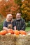 Happy elderly baby boomer couple poses in an autumn scene with a dog and pumkins