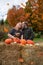 Happy elderly baby boomer couple poses in an autumn scene with a dog and pumkins