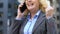 Happy elderly businesswoman gesturing Yes while talking on phone, good news