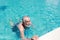 Happy elderly caucasian swimming in pool during retirement holiday with relaxation and smiling