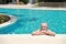 Happy elderly caucasian swimming in pool during retirement holiday with relaxation and smiling. Old man having good time in hotel