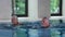 Happy elderly couple swimming in indoor hotel pool