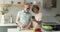 Happy elderly husband cook dinner talk with wife holding phone