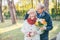 Happy elderly man gives his lady flowers while covering her eyes with palm, she have some present for him